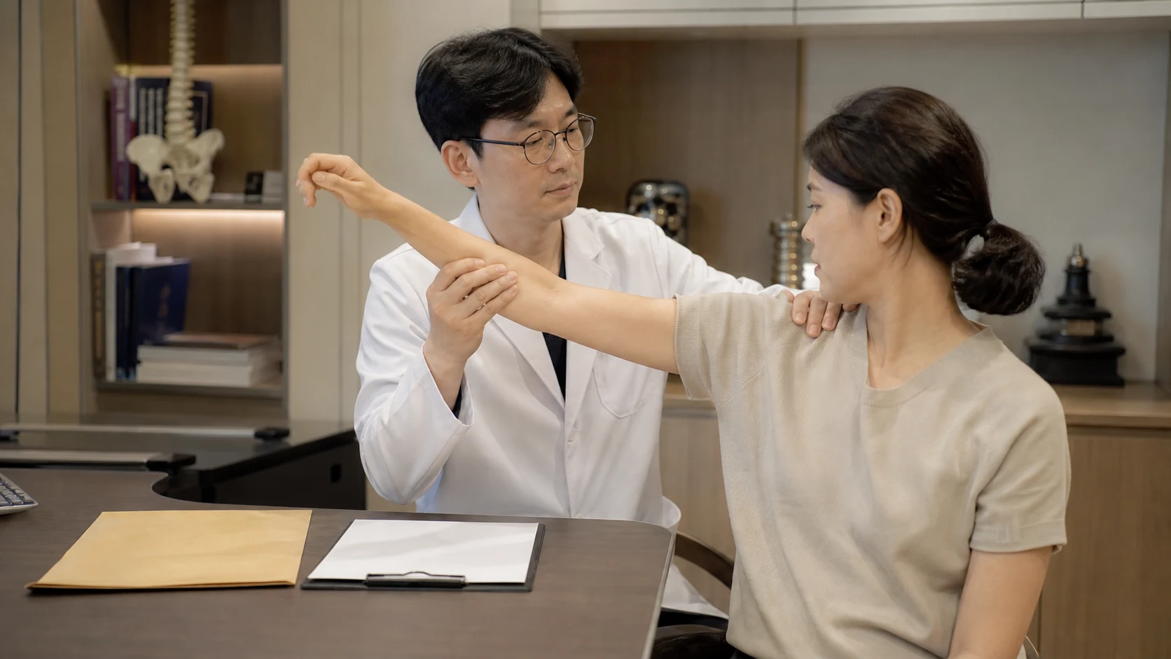 한국인 의료진이 석회화건염 초진에서 어깨 검사 자료와 팔 가동범위를 확인하는 장면