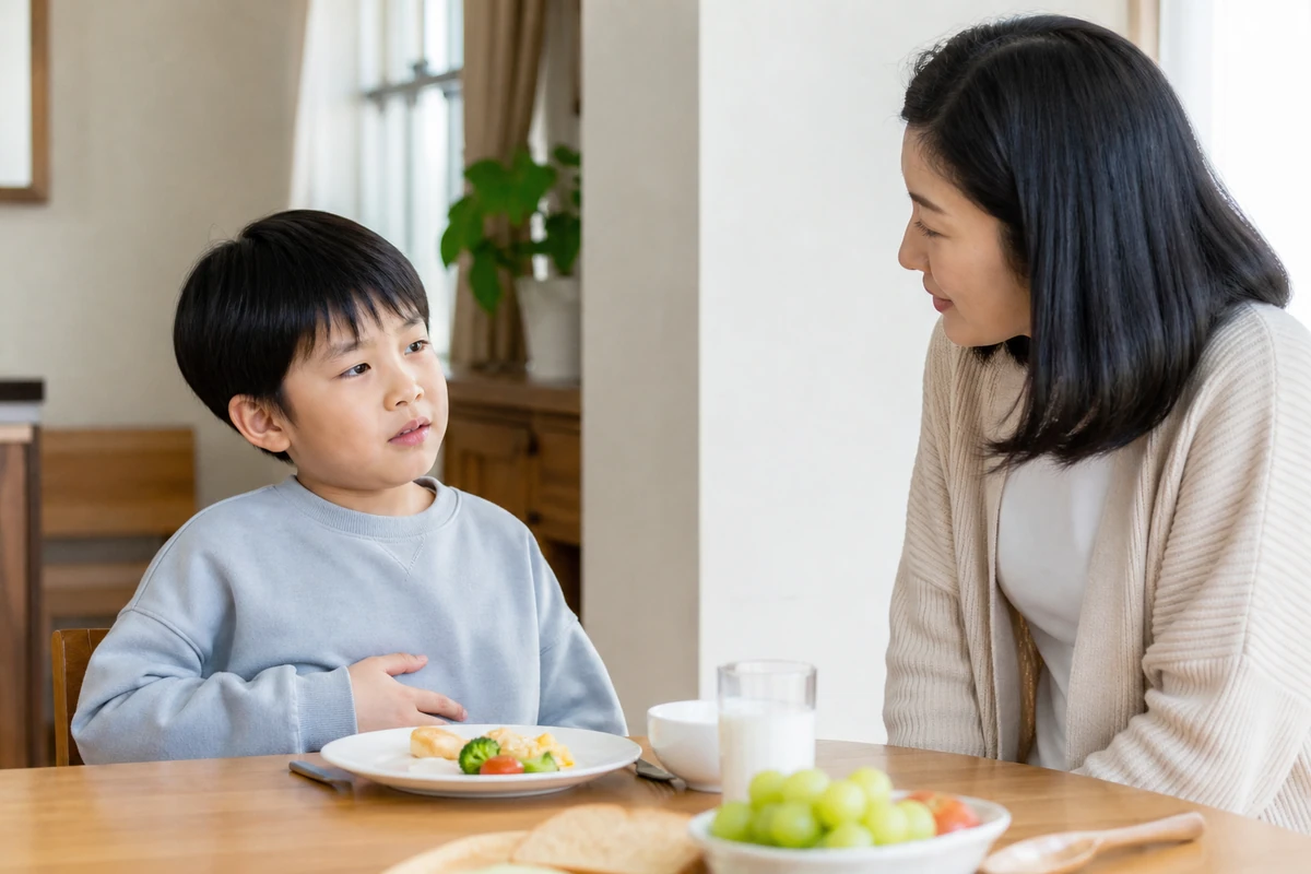 아침 식사를 몇 숟갈 먹고 윗배의 포만감 때문에 멈춘 한국인 아이와 보호자
