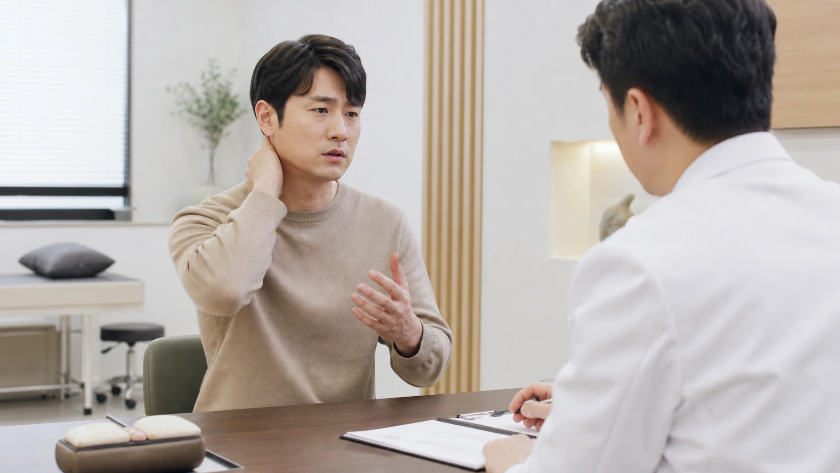 후두신경통 환자가 국내 한의원 진료실에서 목 뒤와 뒤통수 통증을 상담하는 장면