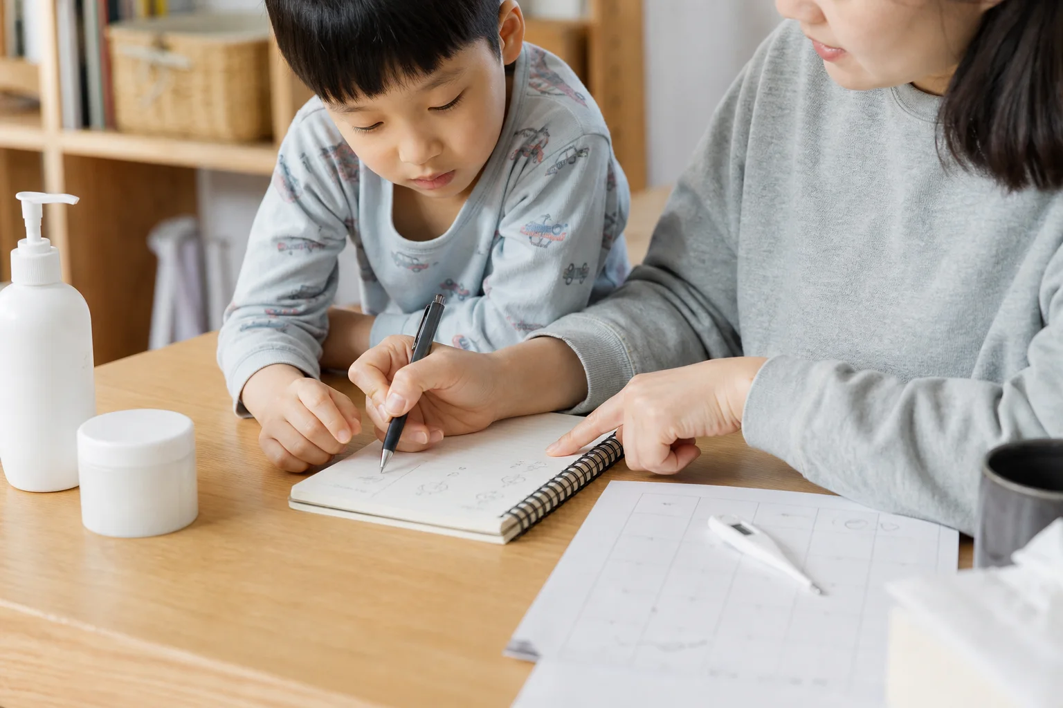 한국인 보호자가 아이의 소아건선 가려움 시간과 보습 기록을 생활 기록장에 적는 사진