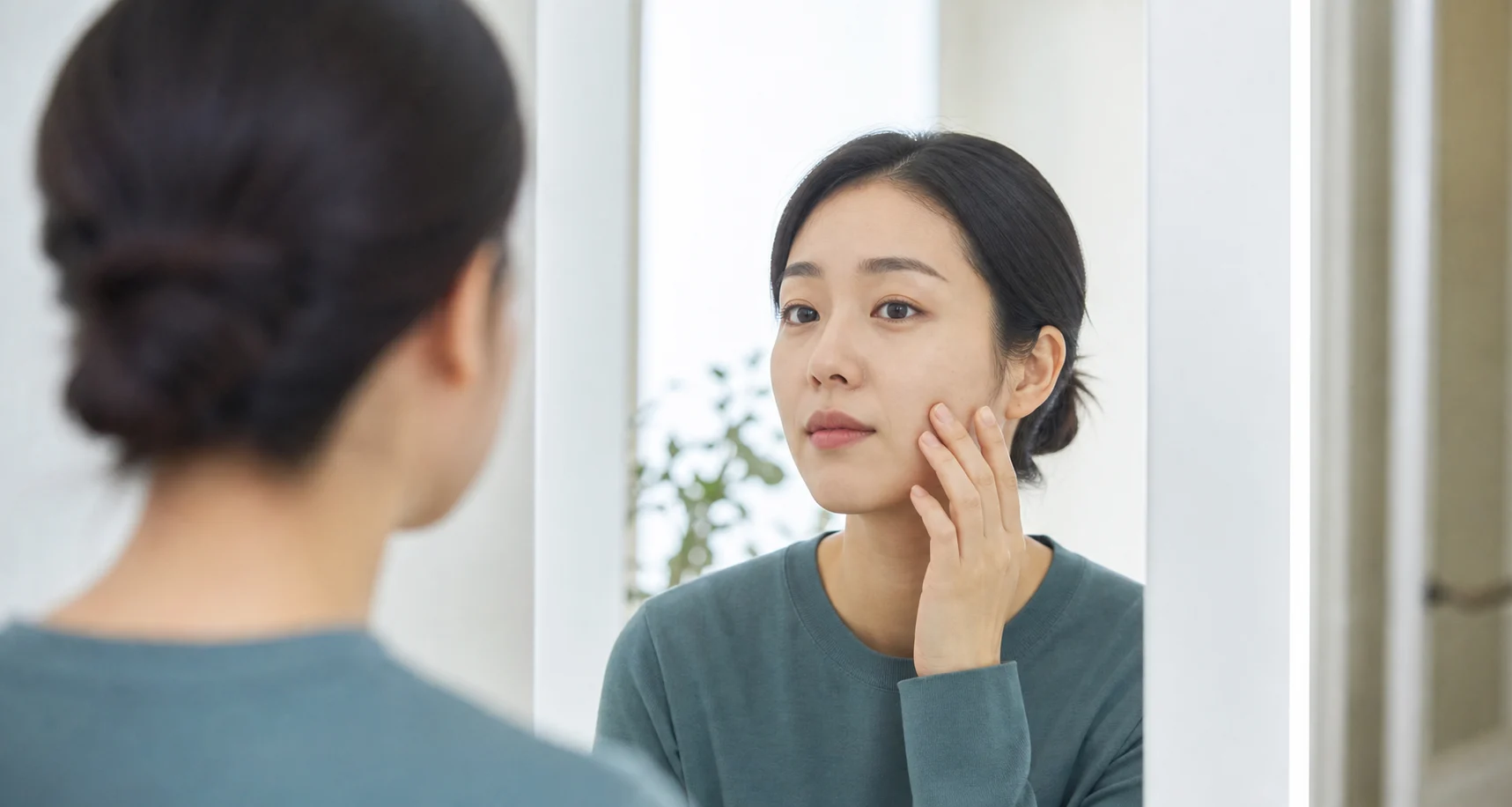 거울 앞에서 한쪽 볼과 입가 움직임을 조심스럽게 확인하는 안면마비 초기 신호 이미지