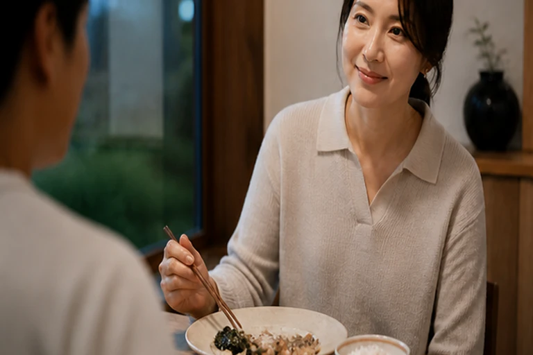 식탁에서 젓가락을 들고 맞은편 사람에게 미소 짓는 여성
